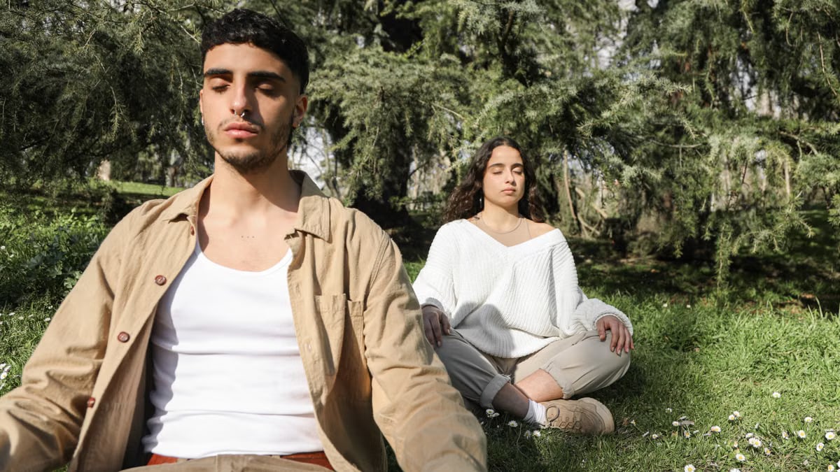 Peaceful scene of a couple meditating outdoors, embracing relaxation and tranquility.